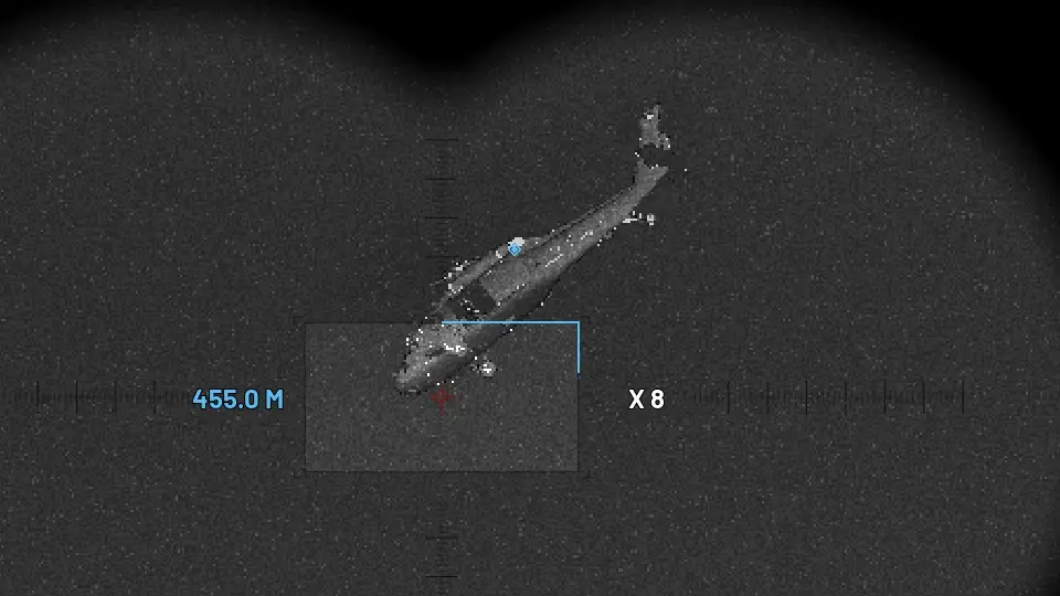 Thermal view of a helicopter glowing white, with the range reading 455 metres